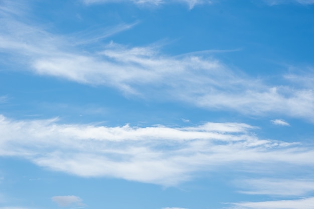 青い空を背景にした本物の柔らかな質感の羽のような雲。夏の日には、水色の空にさまざまな形や大きさの羽毛のようなふわふわの雲がゆっくりと浮かんでいます。