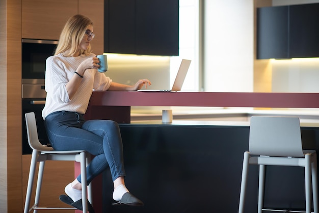 집에서 노트북을 사용하여 휴식을 취하는 커피를 마시는 실제 여성