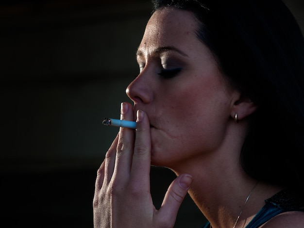 Real young woman smokes on railroad trucks.