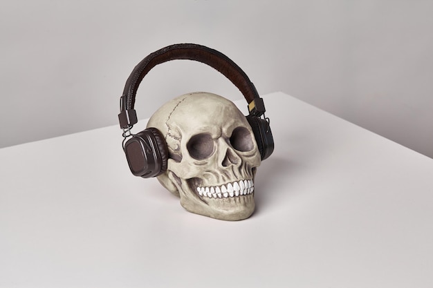 Realistisch model van een menselijke schedel met tanden in een zwarte koptelefoon op een lichte tafel witte achtergrond medische wetenschap of Halloween horror concept close-up shot