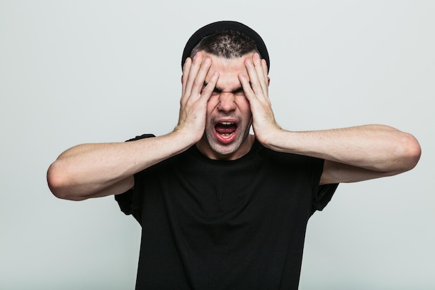 Really annoyed man in black tshirt against grey background