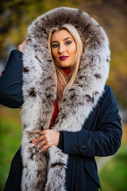 Really warm and cozy expensive clothes luxury segment brand\
luxury fur beauty and fashion woman wear coat with huge furry hood\
fake fur fabric elegant girl walk in autumn park fur garments