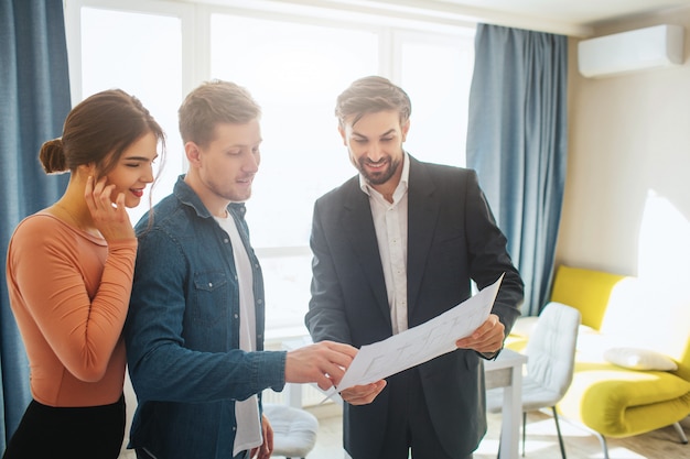 Realtor and couple looking at blueprint