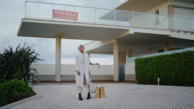 Realtor posing sale house in cloudy day stylish african woman hunting property