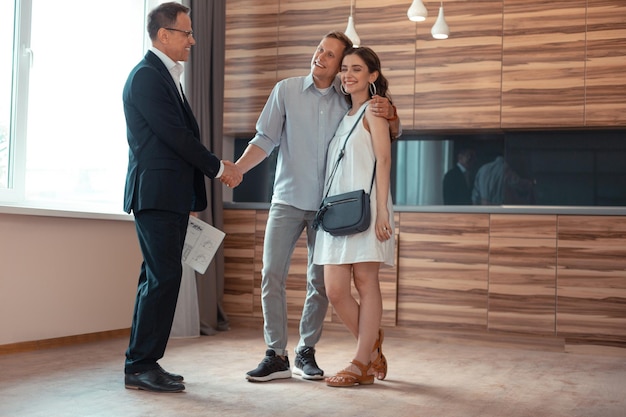 Realtor shaking hand of clients buying the house