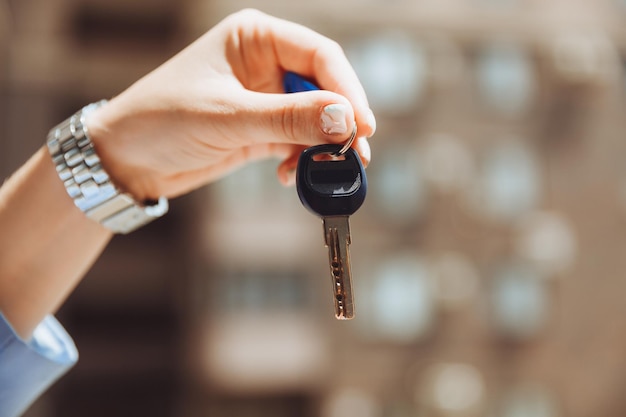 A realtor woman holds the key to an apartment in a new house the owner of the property makes a sale buys the concept of a real estate transaction closeup