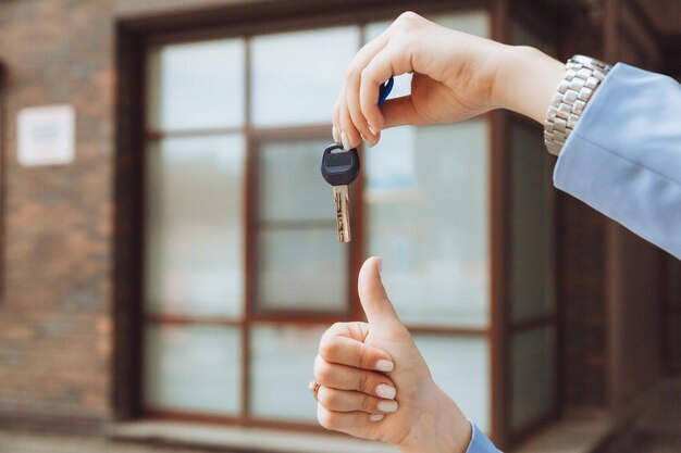 A realtor woman holds the key to an apartment in a new house the owner of the property makes a sale buys the concept of a real estate transaction closeup