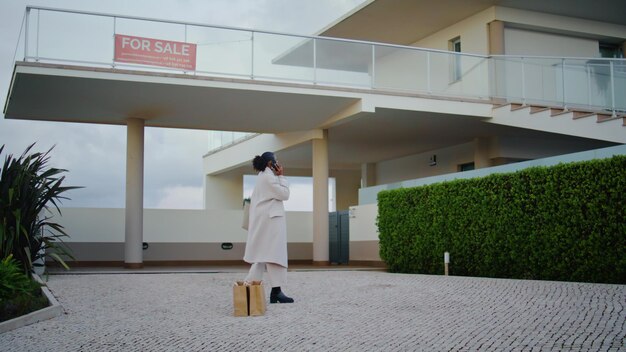 Realtor woman talking phone on house for sale stylish african american calling