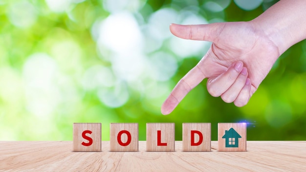 Реалторские агенты вручную ставят кубик с иконой дома и словом "SOLD" Концепция продажи дома, квартиры, рынка недвижимости, недвижимости, инвестиций в недвижимость и ипотеки дома, финансовая концепция.