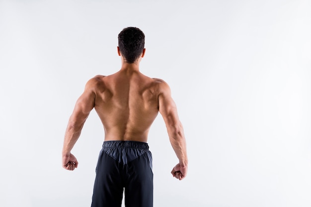 Rear back behind view of sportive tanned guy physical culture steroid protein demonstrating muscles