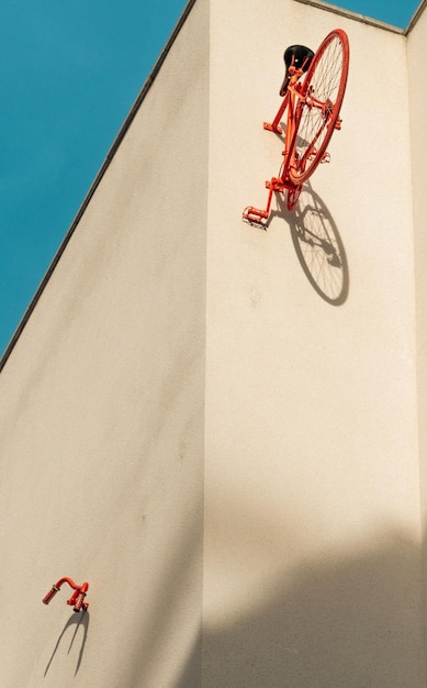 シンプルな建物の壁に固定されたビンテージ自転車の後半部分と赤いハンドルバー