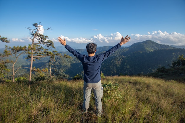 Rear of happy man stand on top mountain looking view with mist and cloud at Doi Langka Luang, Chiang Rai province. soft focus.