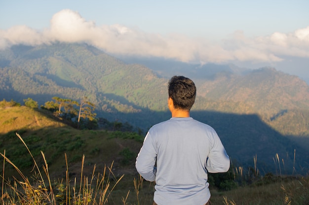 Rear of happy man stand on top mountain looking view with mist and cloud at Doi Langka Luang, Chiang Rai province. soft focus.