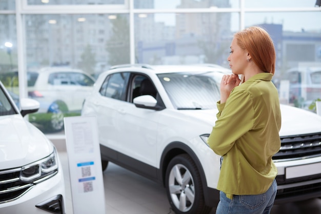 Foto ripresa posteriore di una donna che sceglie un'automobile da acquistare presso un concessionario di auto locale, copia spazio