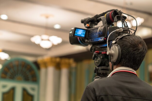 Rear side of Video Cameraman taking photograph to Asian Speaker with casual suit