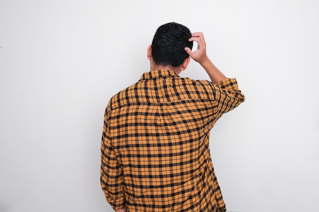 Photo rear view of adult man scratching his head showing confused gesture