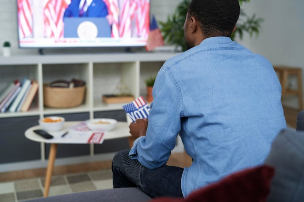 Rear view of affectionate man watching USA election on TV