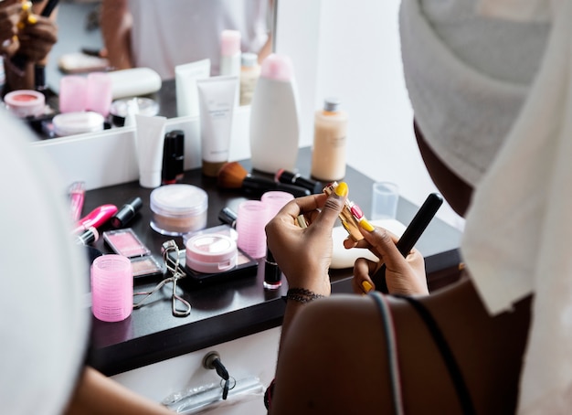 Photo rear view of an african descent woman using a lipstick