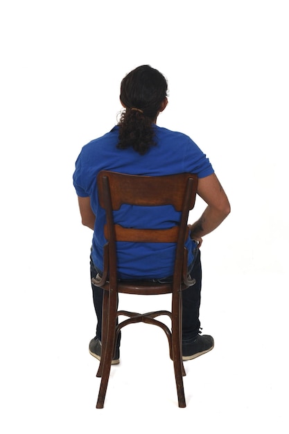 Rear view of aman with ponytail and casual clothing  sitting a chair on white background