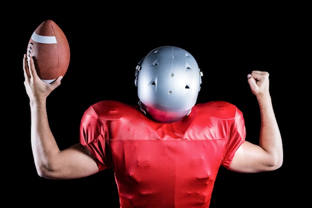 Photo rear view of american football player cheering while holding ball