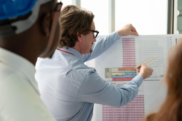 Photo rear view of architect looking at blueprint in office