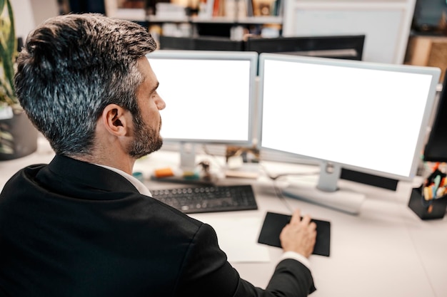 Foto vista posteriore di un architetto seduto nel suo ufficio e che usa il computer per i progetti