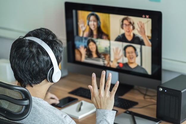 Vista posteriore dell'uomo d'affari asiatico saluta con un collega di lavoro di squadra in videoconferenza