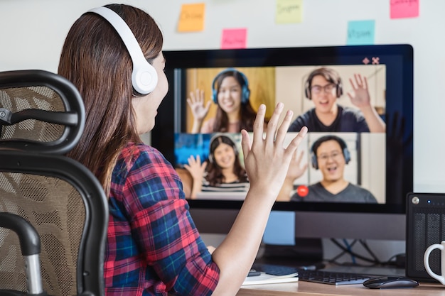 Rear View of Asian Business woman say hello with teamwork colleague in video conference