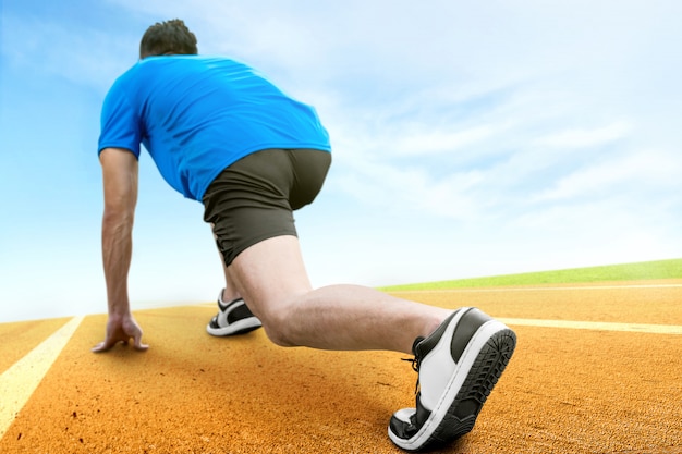 Rear view of Asian runner man ready to run on the running track