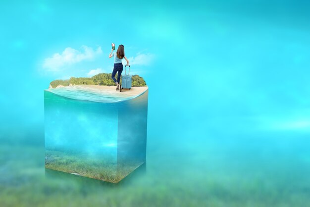 Rear view of Asian woman with a suitcase holding ticket and passport on the beach with an underwater view of blue water on the ocean. Environment concept