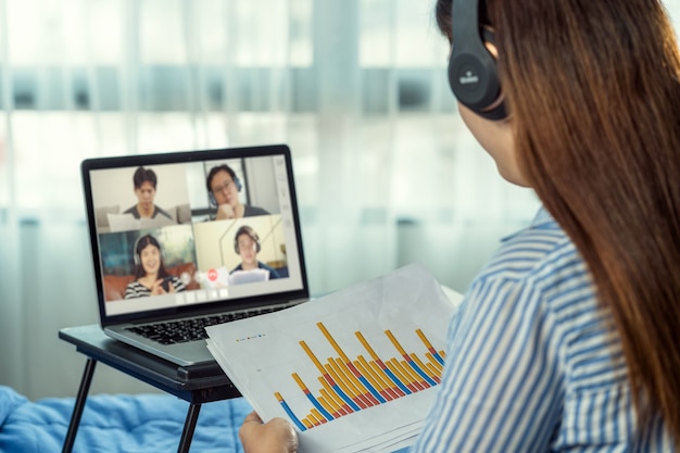 Rear view of Asian woman working and online meeting via video conference with colleague