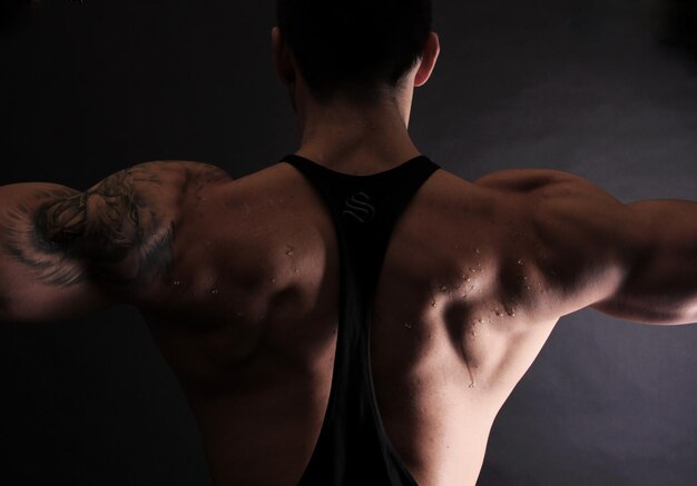 Rear view of athlete standing against black background