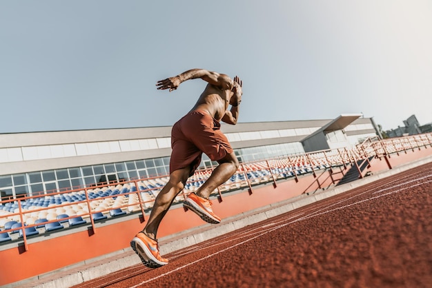 Photo rear view of an athlete starting his sprint on an allweather running track