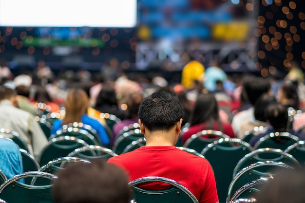 Rear view of Audience in the conference hall or seminar meeting which have Speakers on the stage, bu