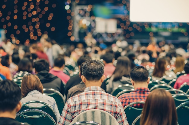 Rear view of Audience in the conference hall or seminar meeting which have Speakers on the