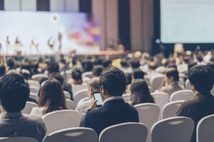 Rear view of audience listening speakers on the stage in the conference hall or seminar meeting