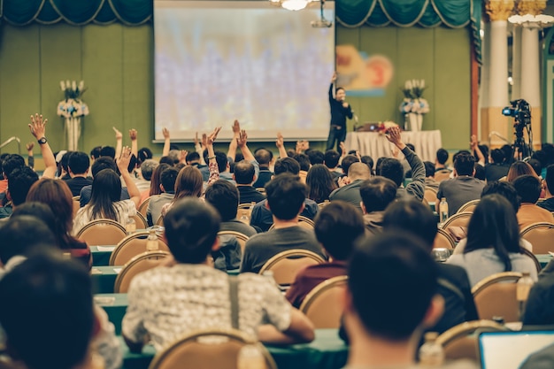 Rear view of Audience showing hand to answer the question from Speaker on the stage