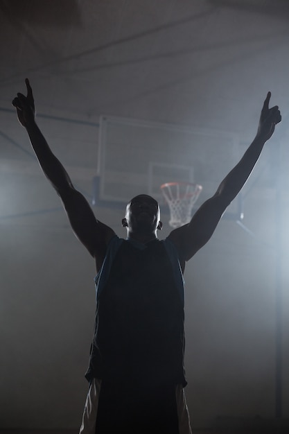 Rear view of a basketball player with his arms in the air