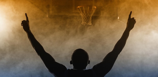 Retrovisione di un giocatore di pallacanestro con le sue braccia nell'aria