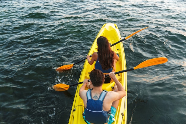 Foto vista posteriore della bella giovane coppia in kayak