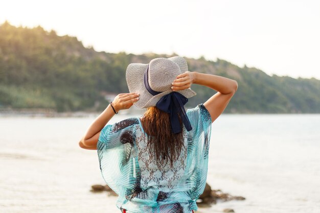 Rear view of a beautiful young woman is relaxing on the beach in a sunny day.