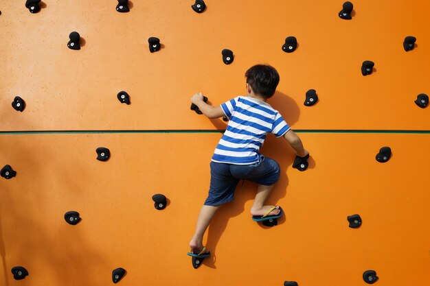 Photo rear view of boy climbing wall