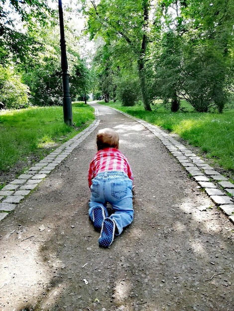 Задний вид мальчика, ползающего по дороге.