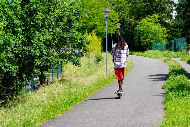 Rear view of boy girl riding public rental electric scooter in cycle path city environment