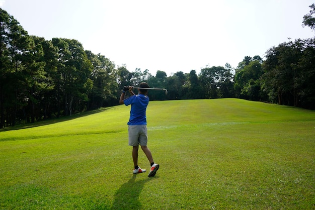 Rear view of boy on golf course against sky