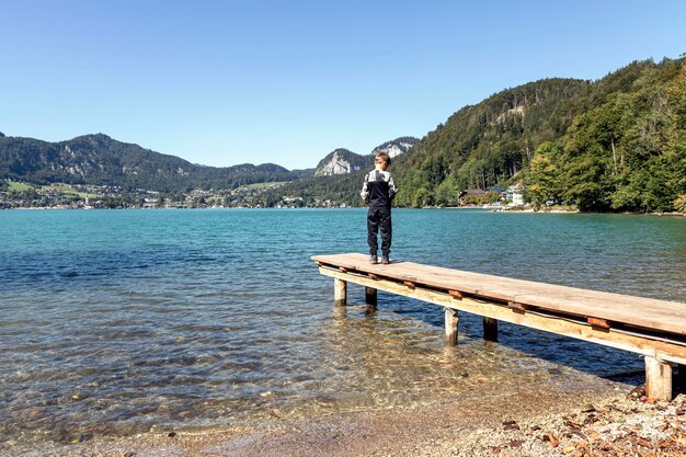 Foto vista posteriore di un ragazzo che guarda il lago contro il cielo