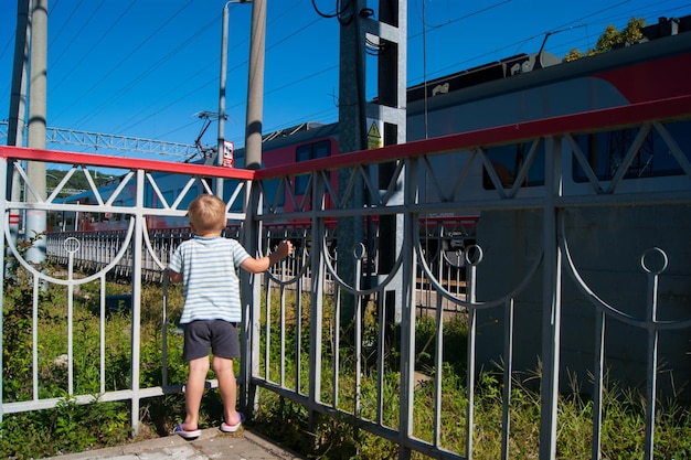 Rear view of boy looking at train while standing in balcony