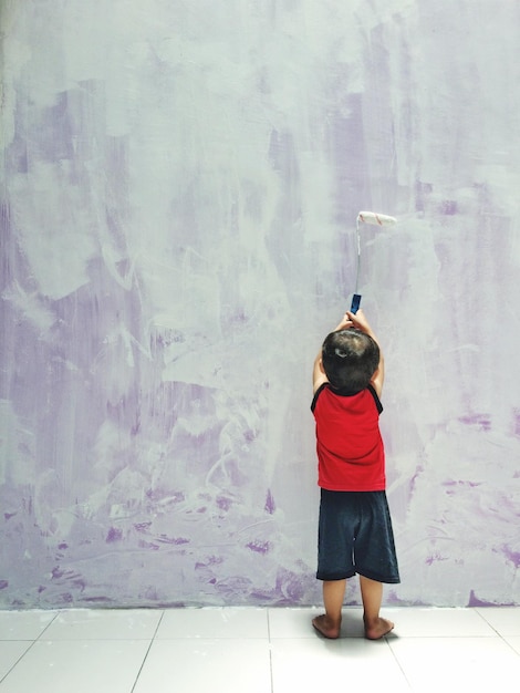rear view of boy painting wall