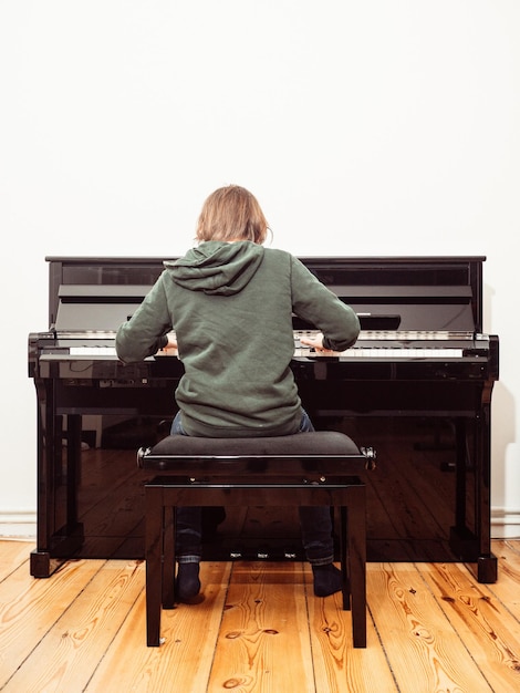 Foto vista posteriore di un ragazzo che suona il pianoforte a casa