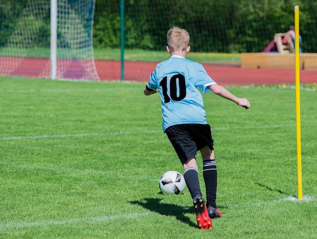 Photo rear view of boy playing soccer at grassy field